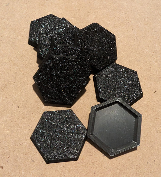Set of black 3D printed hex bases for miniature games, featuring a textured surface and smooth edges